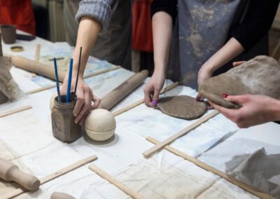 A group of students taking a ceramic making class wearing aprons